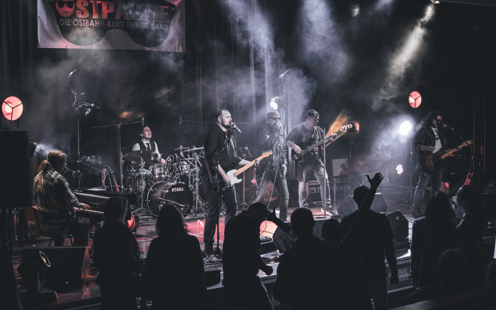 Foto der Band "Ostpartie" auf der Bühne mit Gitarren, Schlagzeug und Mikrofonen