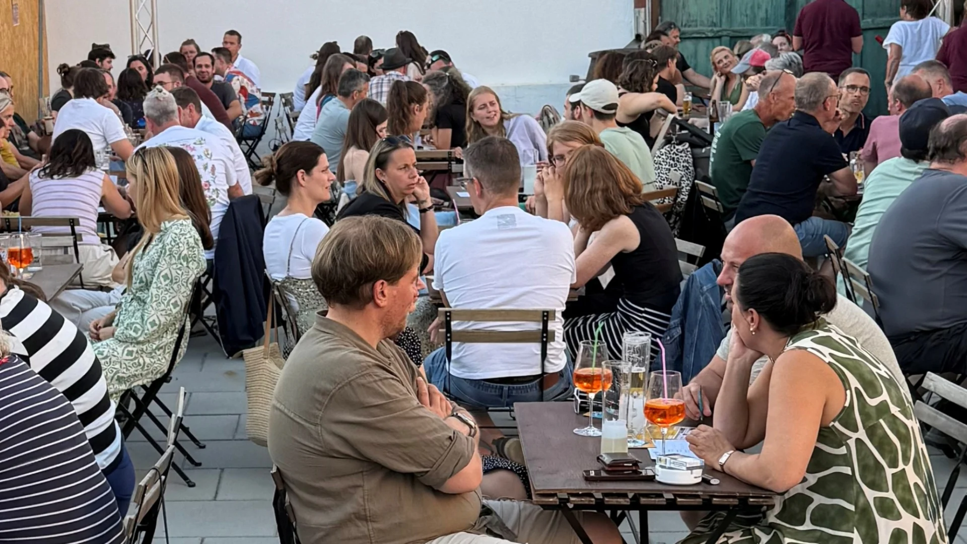Personen sitzen an Tischen in einem Innenhof